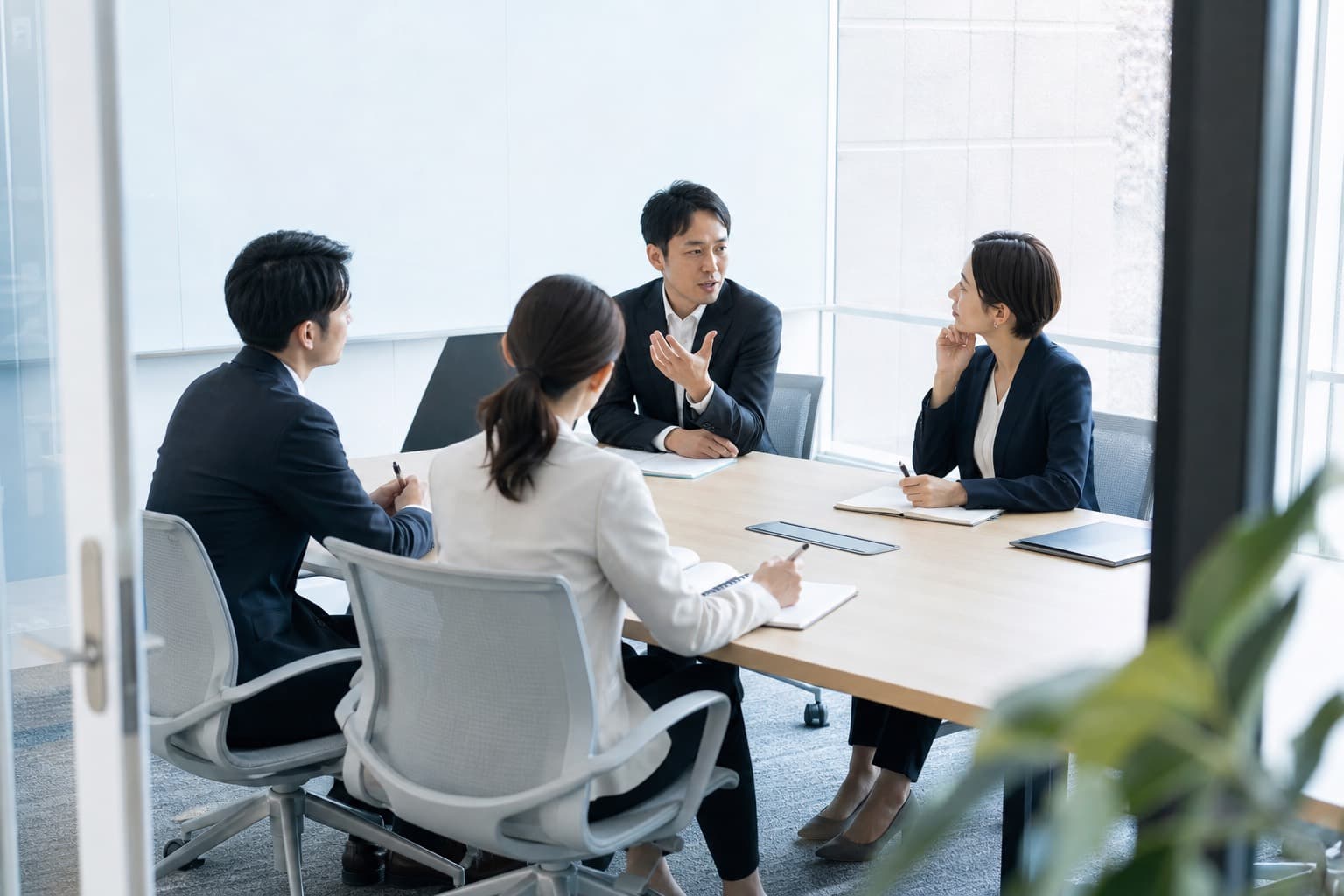 明るい会議室で経営層と管理職が対話する様子
